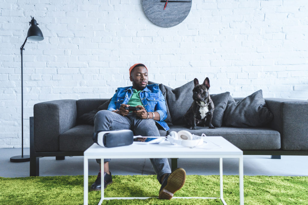 Man with bulldog and VR gear on couch